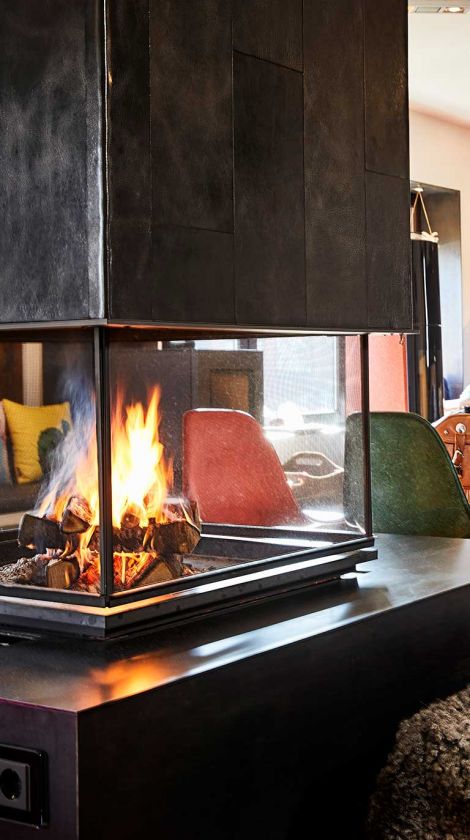 Blick ins Wohnzimmer wo ein Feuer im Ofen Bruckmühl brennt